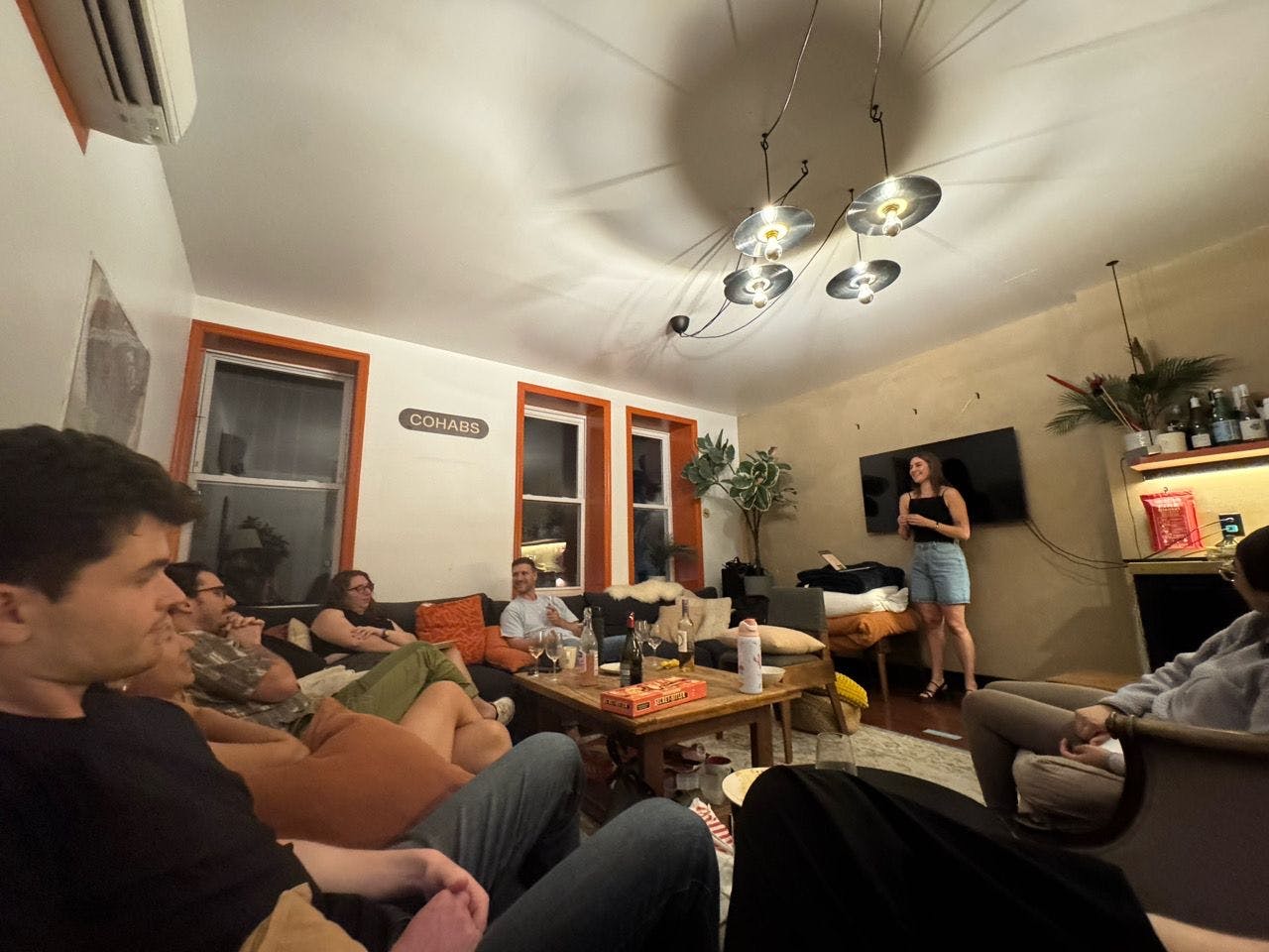The room mid-talk — guests gathered under record-shaped pendant lights