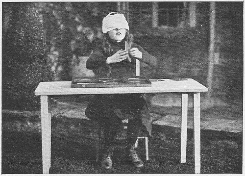 A blindfolded child identifying a geometric inset by touch alone
